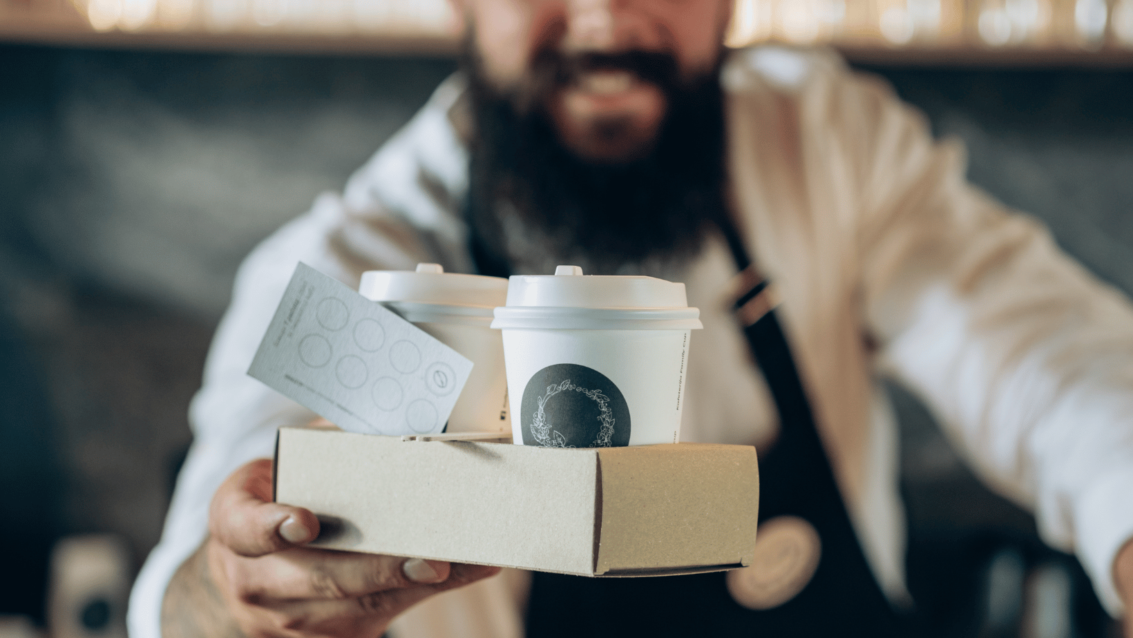 Barista holding coffee cups and loyalty punch card 