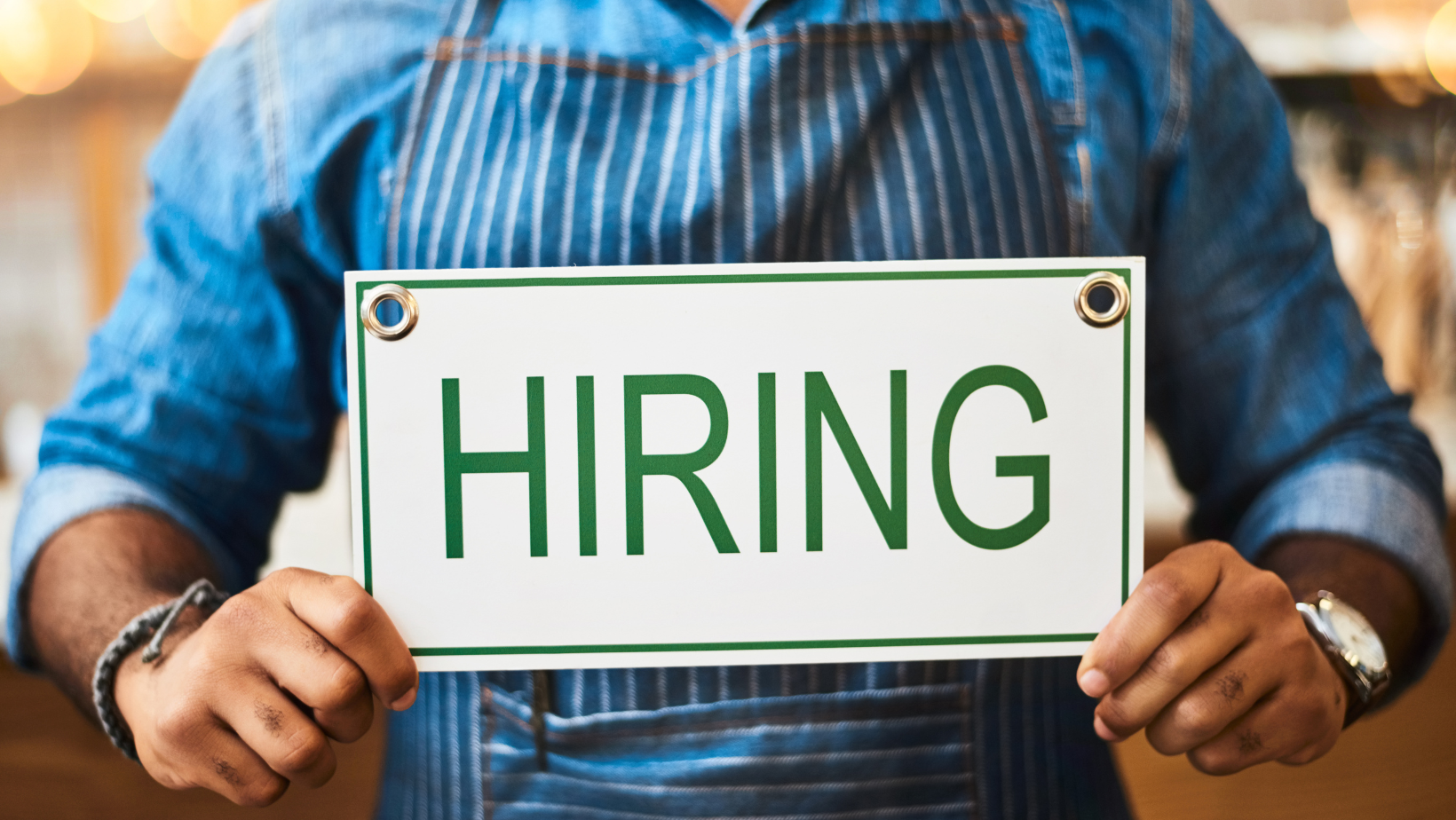 Hands holding a hiring sign at cafe