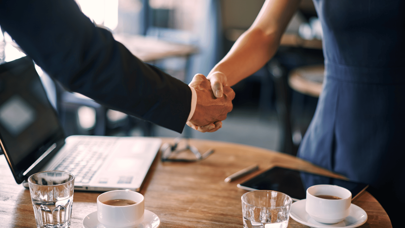 People shaking hands at an interview in a coffee shop