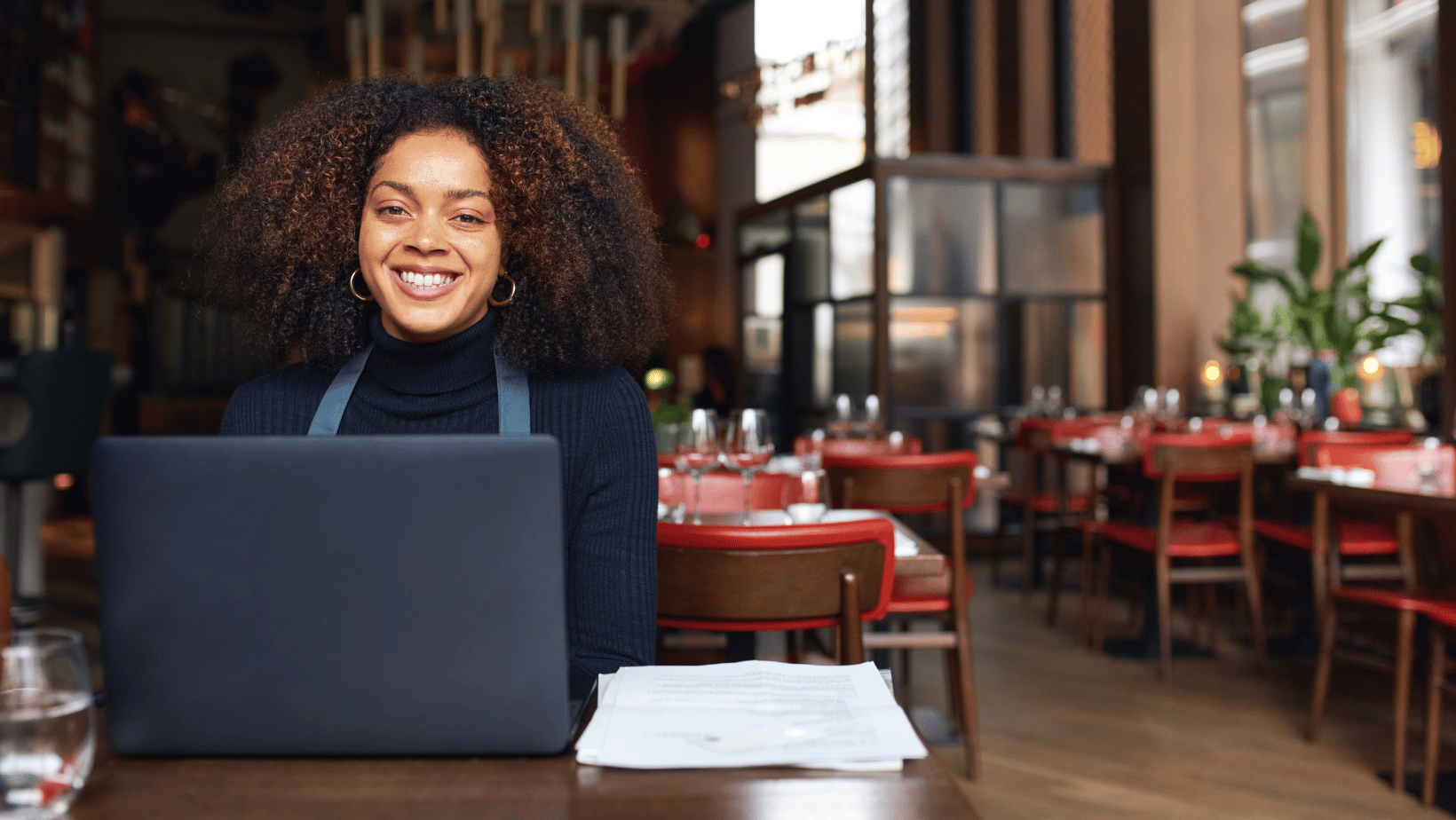 Smiling restaurant owner writing an email marketing campaign on a computer